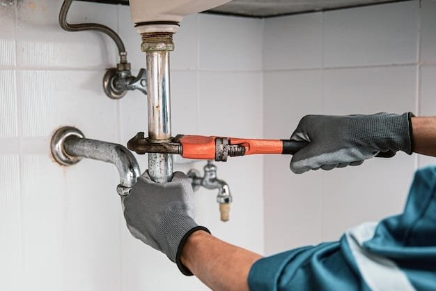 Plumber in a blue hard hat and work gloves repairing brass water pipes and valves